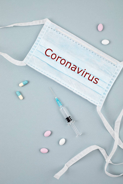 Coronavirus 2019-nCoV text on disposable medical mask, personal protective equipment, syringe filled medicine or vaccine and medicine pills. Virus concept - Foto, immagini