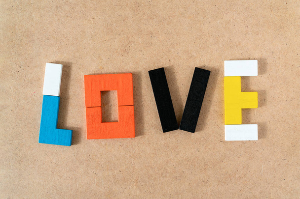 Aşk kelimesi Kraft karton arka planındaki renkli ahşap tuğlalardan yapılmış. Üst manzara, düz uzanma. - Fotoğraf, Görsel