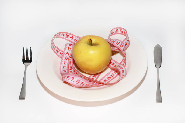 manzana en un plato y una cinta de centímetro
 - Foto, Imagen