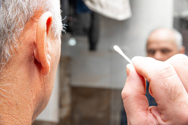 Cleaning the ears with an ear stick. The concept of caring for ear hygiene. Blocked ear, hearing problems. Improper ear cleaning. - Foto, immagini
