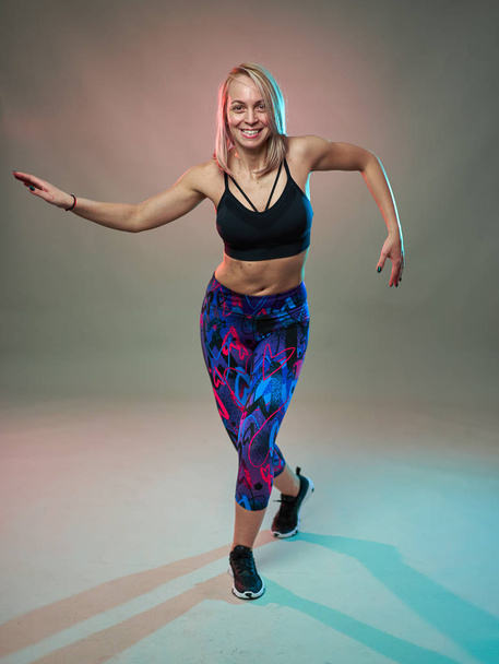 Fitness model doing aerobic exercises and dancing, studio shot - Foto, imagen