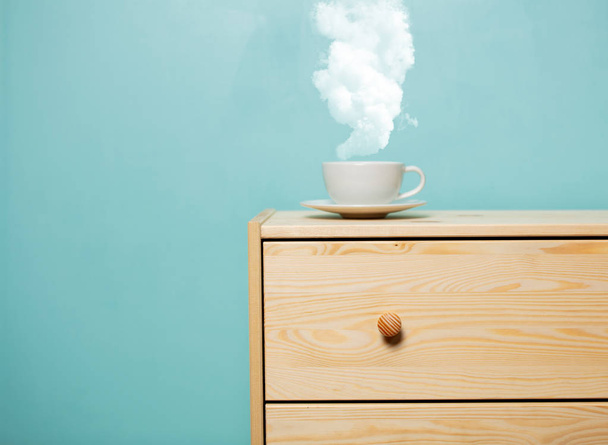 Xícara de café com vapor na mesa de cabeceira de madeira
 - Foto, Imagem
