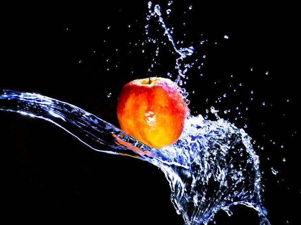 an apple is shot in studio with water. a very fresh motif. - Фото, изображение