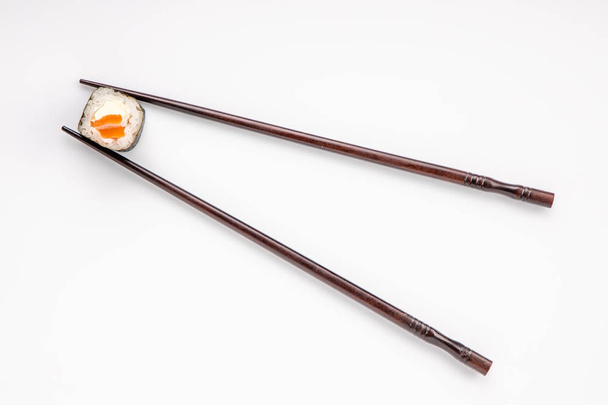 roll between chopsticks for sushi on a light background for the menu1 - Photo, Image