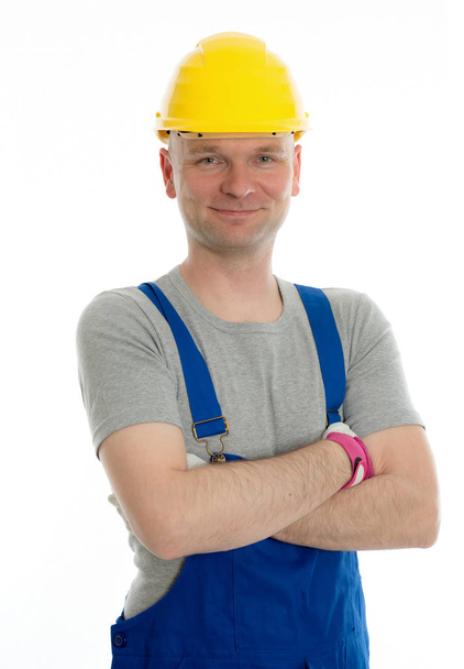young workman in blue dungarees and yellow hard top - Фото, зображення