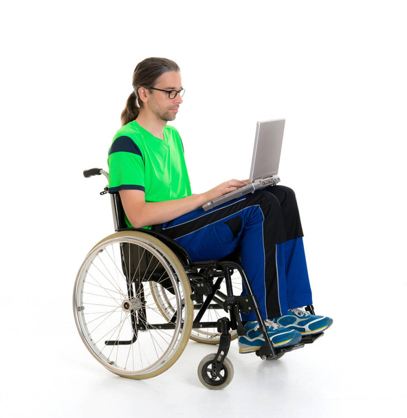 young man in a wheelchair in front of white background with computer - Valokuva, kuva