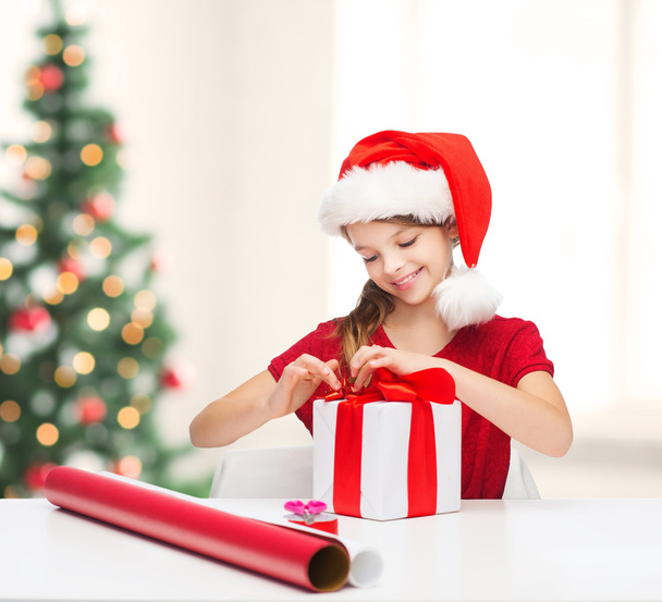 Smiling girl in santa helper hat with gift box - Foto, Bild