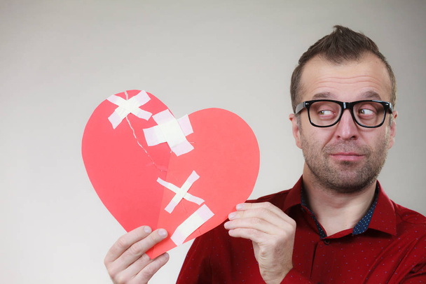 Thoughtful man holds broken heart - Фото, изображение