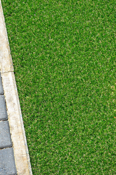 A section of artificial green grass and stone edging seen from above - Fotó, kép
