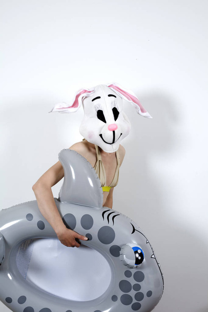 Rabbit woman playing with an inflatable shark - Foto, imagen