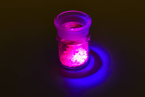 Fluorescent organic materials of red, yellow and green color for production OLED inside glass bottle in UV light. - Photo, Image