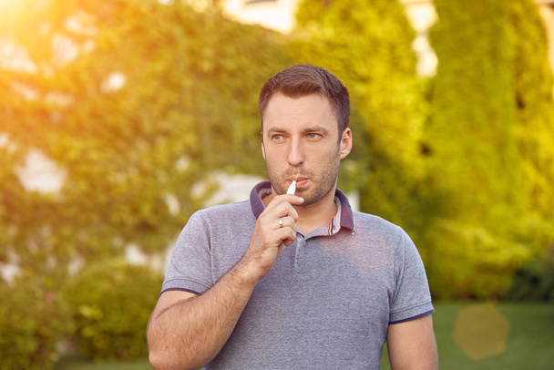 Elektronische sigaretten, sigarettentechnologie. Tabak Iqos-systeem. Close-up van een man die een elektrische hybride sigaret rookt met een hittestok. Nieuw verwarmingssysteem voor tabak zonder verbranding. - Foto, afbeelding