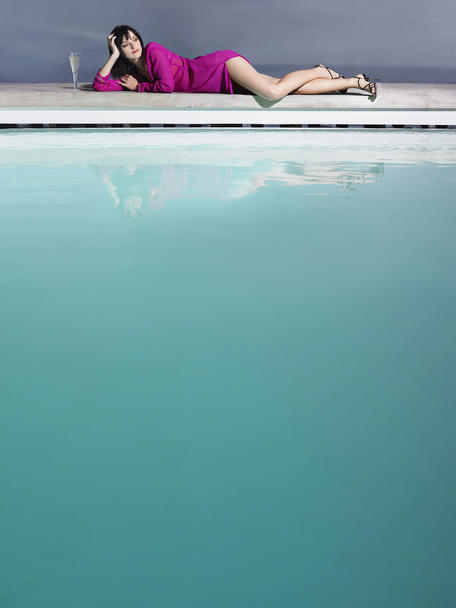 Жінка сидить біля басейну
 - Фото, зображення