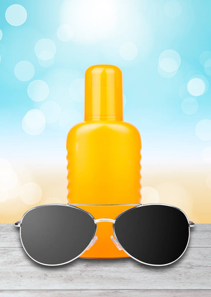 sun lotion with sunglasses and a beach background - Fotó, kép