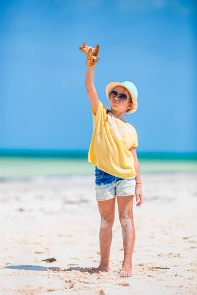 Niña feliz con avión de juguete en las manos en la playa blanca
 - Foto, imagen