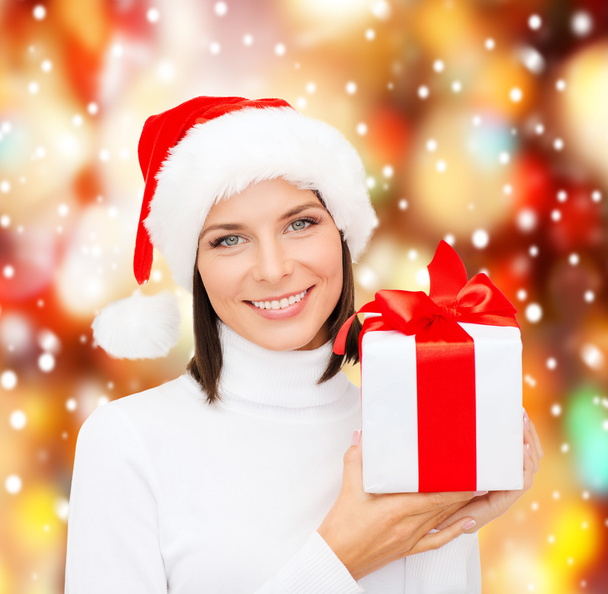 Femme souriante en santa chapeau d'aide avec boîte cadeau
 - Photo, image