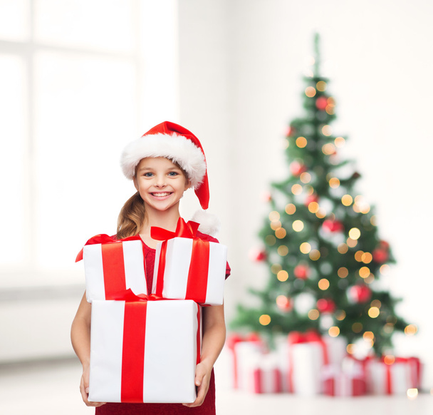 Girl in santa helper hat with many gift boxes - Photo, image