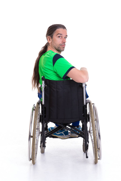 young man in a wheelchair in front of white background from the back - Foto, Bild