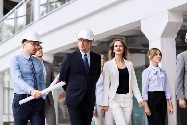 business team in helmets walking along office - Photo, image