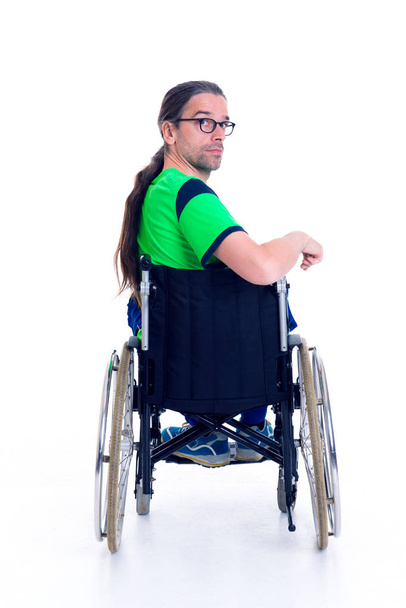 young man with glasses in a wheelchair in front of white background from the back - 写真・画像