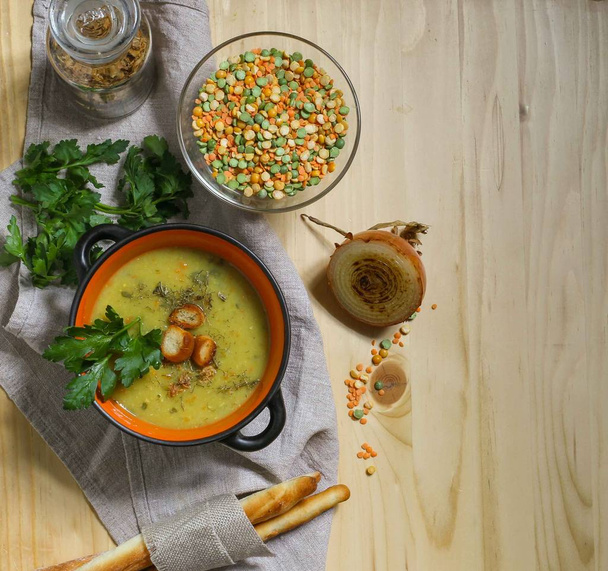 鍋の豆とレンズ豆のマッシュスープと木のテーブルの上のリネンナプキンのパンスティック - 写真・画像