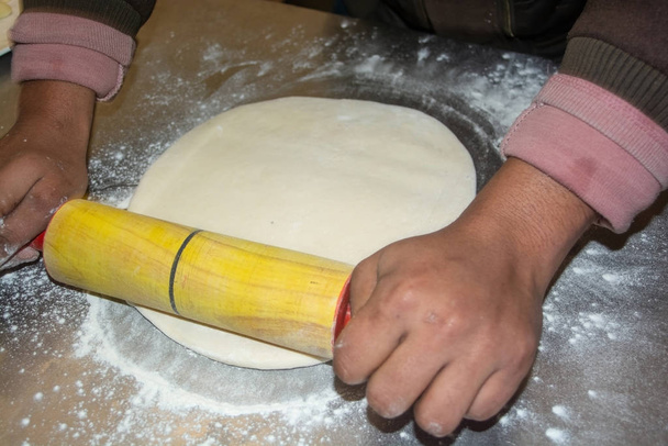 Рабочий катит тесто на пиццу
  - Фото, изображение