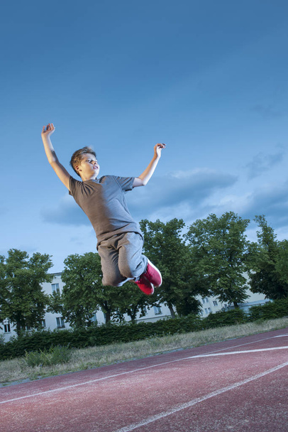 full body view of a young male teenager with a leap into the air on the sports field - Zdjęcie, obraz