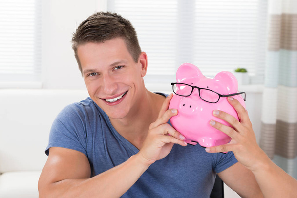 Portrait Of Young Happy Man Holding Pink Piggybank - Fotoğraf, Görsel