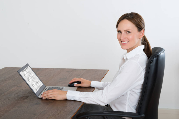 Happy Businesswoman On Chair Working On Laptop At Wooden Desk - Foto, imagen