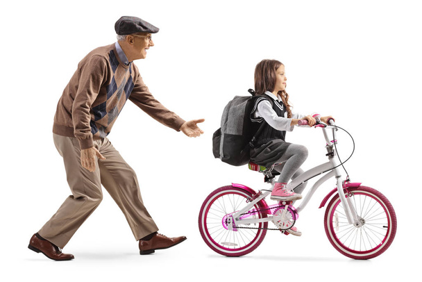 Grandfather teaching a girl to ride a bicycle - Fotoğraf, Görsel