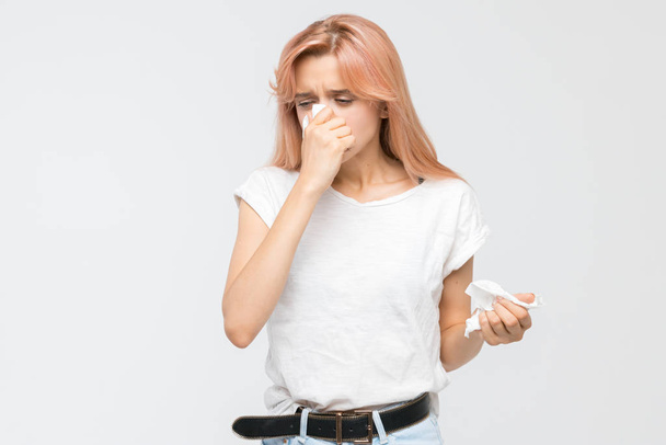 Studio portret młodej blondynki dmuchającej nos w papierową serwetkę. Epidemia przeziębienia, kichania, objawów alergii, grypy, nieżytu nosa, chorób, rozpaczliwie chorych. Koncepcja opieki zdrowotnej i medycyny - Zdjęcie, obraz