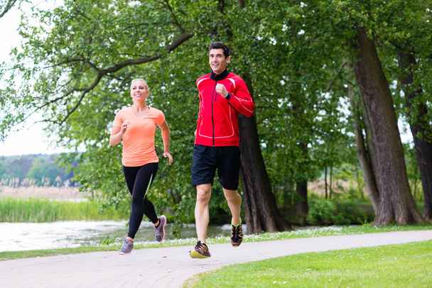 man and woman jogging together on forest path outdoors - Valokuva, kuva