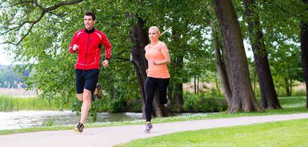 man and woman jogging together on forest path outdoors - Foto, imagen