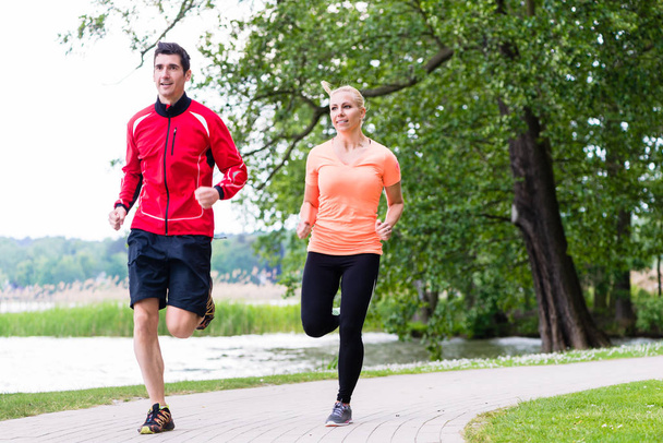 man and woman jogging together on forest path outdoors - Photo, Image