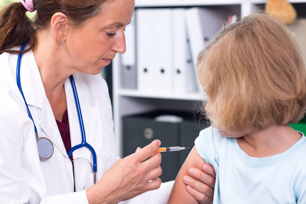 female pediatrician in white lab coat injected a medicament - Foto, Bild