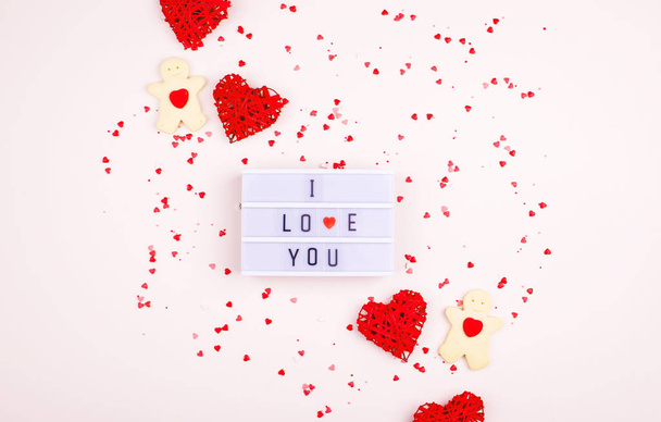 Ein sanfter Hintergrund mit Herzen, einem Geschenk, einem Leuchtkasten und Worten. Valentinstag - Foto, Bild