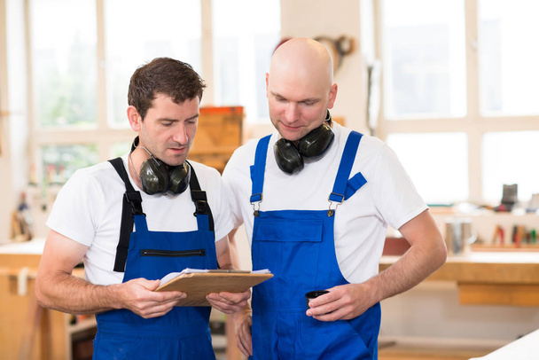 two worker in blue dungarees in a carpenter's workshop - Fotografie, Obrázek