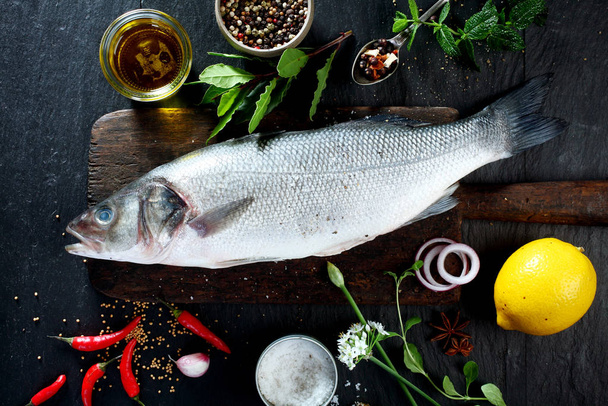 High Angle View of Fresh Raw Whole Fish on Rustic Wooden Cutting Board Surrounded by Fresh Herbs and Spices for Seasoning and Garnishing - Foto, immagini