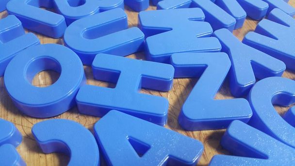 Zestaw plastikowych liter alfabetu umieszczonych na drewnianej podłodze - Zdjęcie, obraz