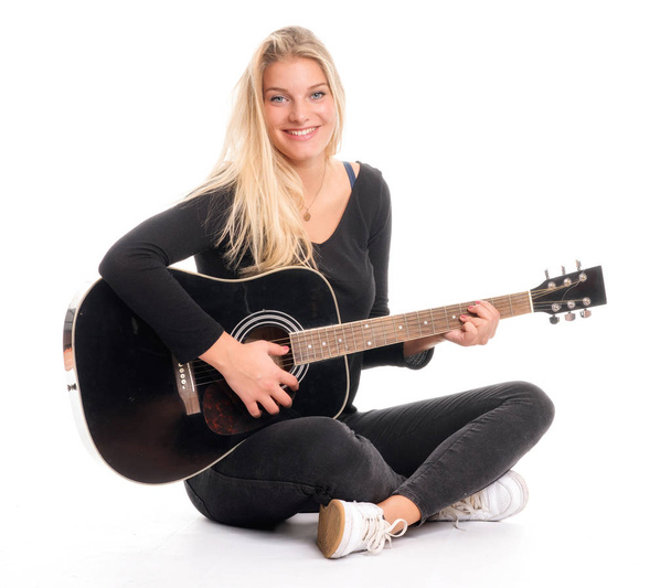 pretty blond girl sitting in tailor's seat and playing guitar - Fotoğraf, Görsel