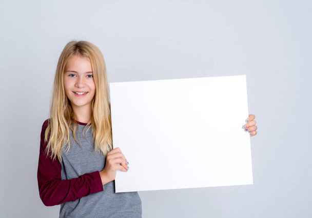 nice blond girl in front of gray background showing a white sign - Foto, immagini