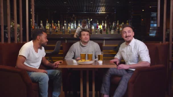 Freunde sitzen an der Bar, trinken Bier und gucken Fußball bei einer Wette - Filmmaterial, Video
