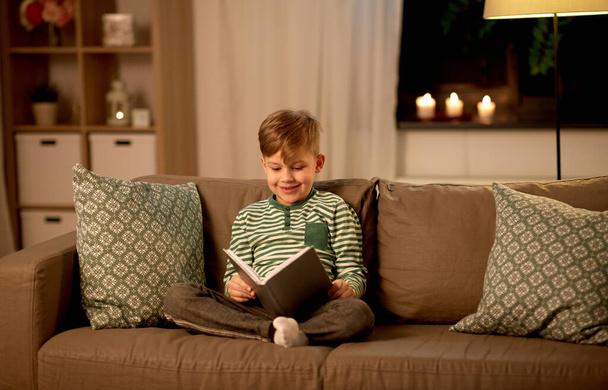 happy little boy reading book at home - Foto, afbeelding