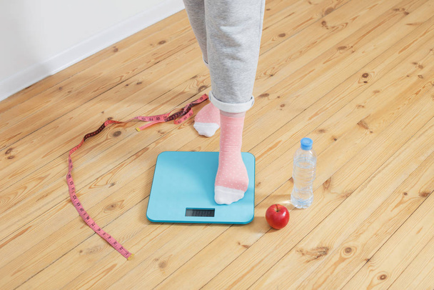 young woman on electronic scales on  wooden floor - Foto, Bild