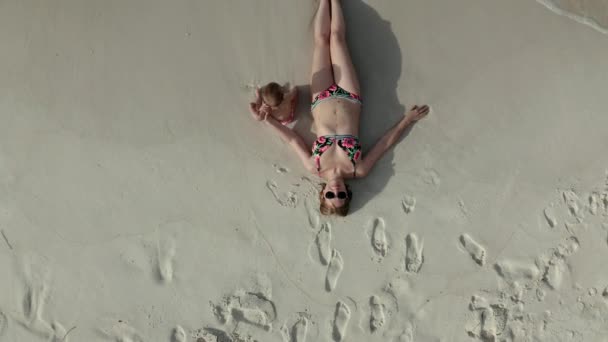 Veduta aerea della donna sdraiata sulla spiaggia con la sua bambina
 - Filmati, video
