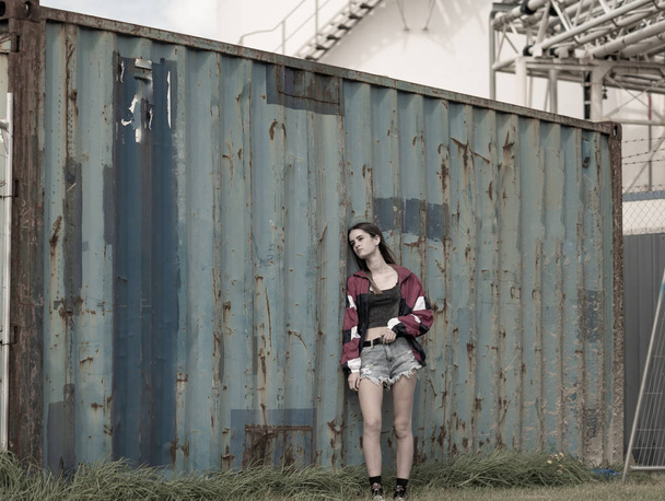 Menina adolescente moderna em pé pelo velho contêiner de carga
 - Foto, Imagem