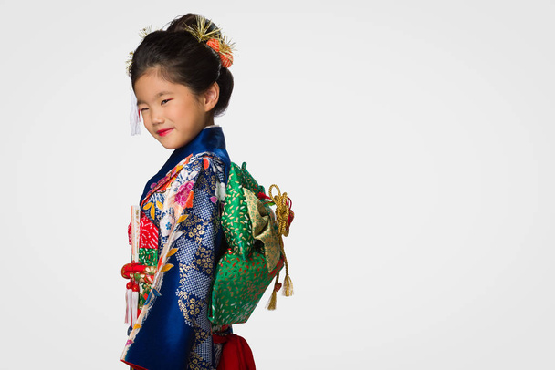 A cute young Japanese girl wearing a Kimono on a white background. - Фото, изображение