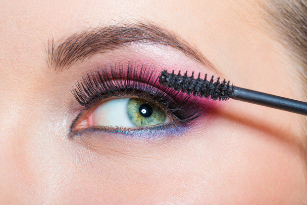 Close up of female eye and brush applying mascara - Zdjęcie, obraz
