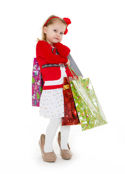 Happy pretty little child with shopping bags stands on a white background. 3 year old. - Foto, Bild