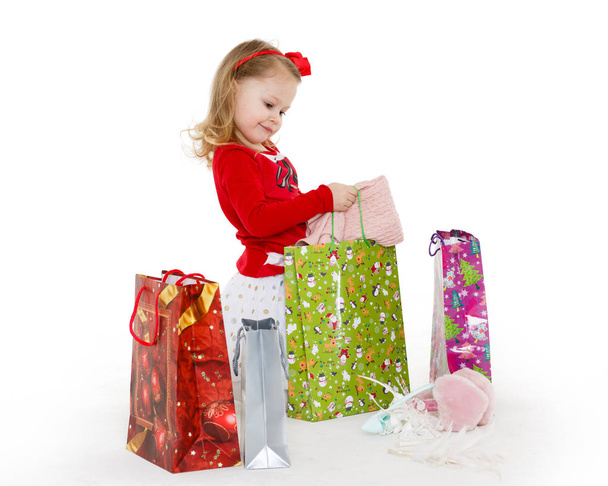 Happy pretty little child with shopping bags sits on a white background. 3 year old. - Foto, imagen